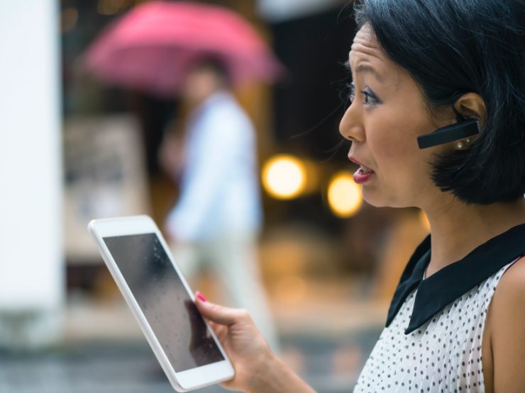 Woman holding a tablet and talking via a blue tooth headset