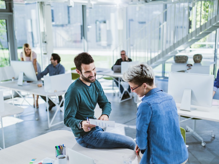 Two people sitting together in an open plan office