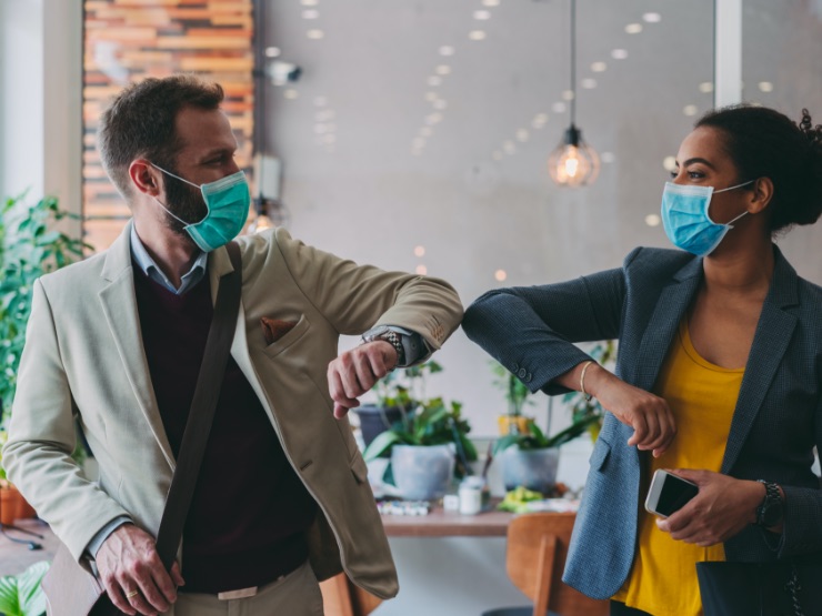 People wearing in masks bumping elbows as a greeting