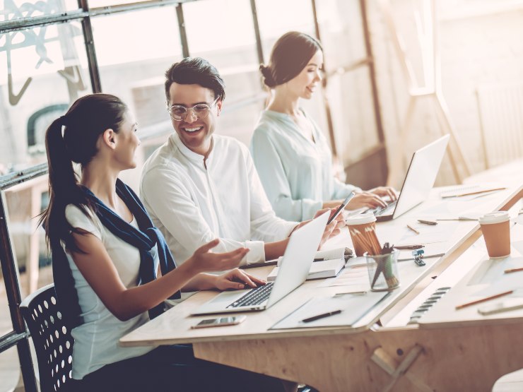 Three people sitting together at a work desk